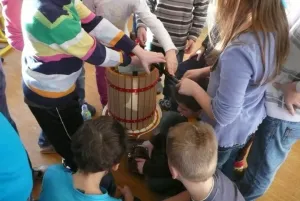 Utahováním šroubu se jablečná drť stlačuje a mošt vytéká do džbánku.